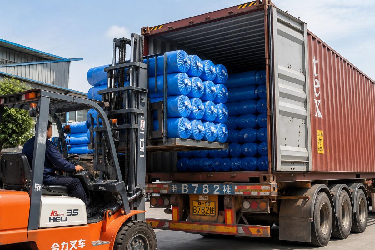 A shipment of HDPE woven tarpaulin rolls being loaded into a shipping container for international delivery