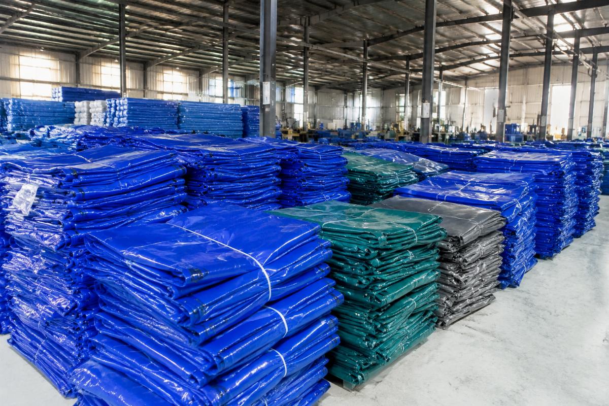 Finished custom size PVC tarpaulin covers stacked in a factory warehouse